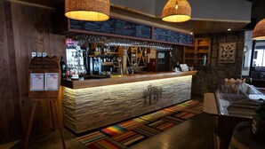 A bar area with a wooden counter, hanging lights, and a menu board. - Colorado Apart Hotel (Lo Barnechea)