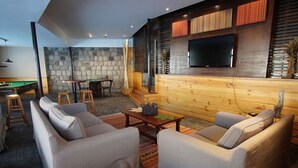 A modern living room with a pool table, comfortable seating, and a flat-screen TV mounted on the wall. - Colorado Apart Hotel (Lo Barnechea)