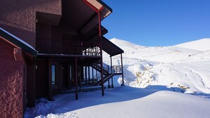 A snow-covered building with a staircase leading to a balcony. - Colorado Apart Hotel (Lo Barnechea)