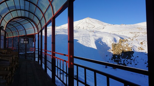 A covered wooden deck with a view of a snow-covered mountain. - Colorado Apart Hotel (Lo Barnechea)