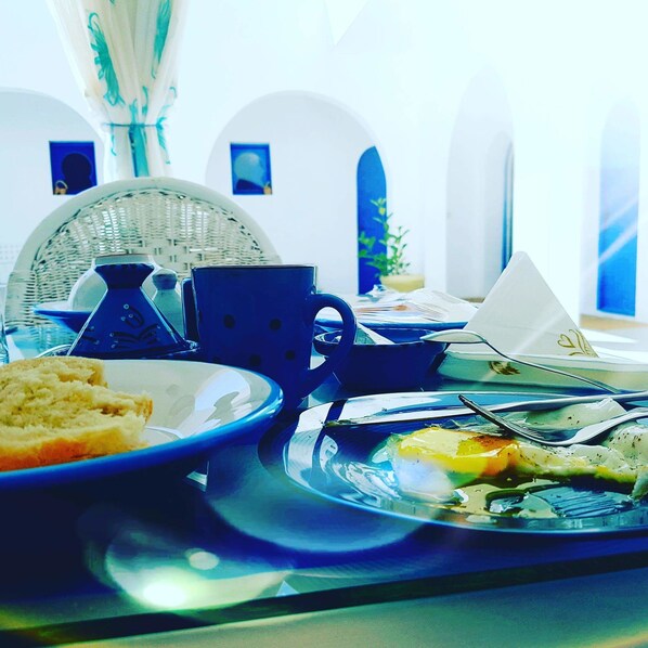 Un desayuno con un plato de comida, una tetera, una taza y un tenedor sobre una bandeja.