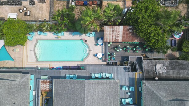 An aerial view of a hotel with a swimming pool, outdoor seating, and surrounding greenery. - Upper Deck Hotel and Bar - Adults Only (South Padre Island)