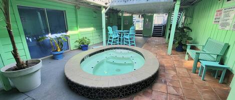 A spa area with a hot tub, seating, and potted plants.