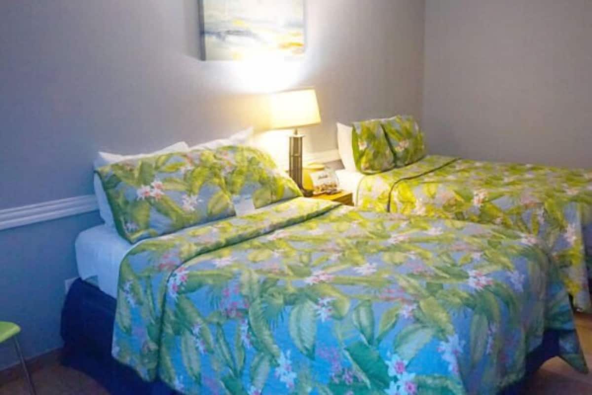 A room with a bed, a nightstand, a lamp, and a chair.