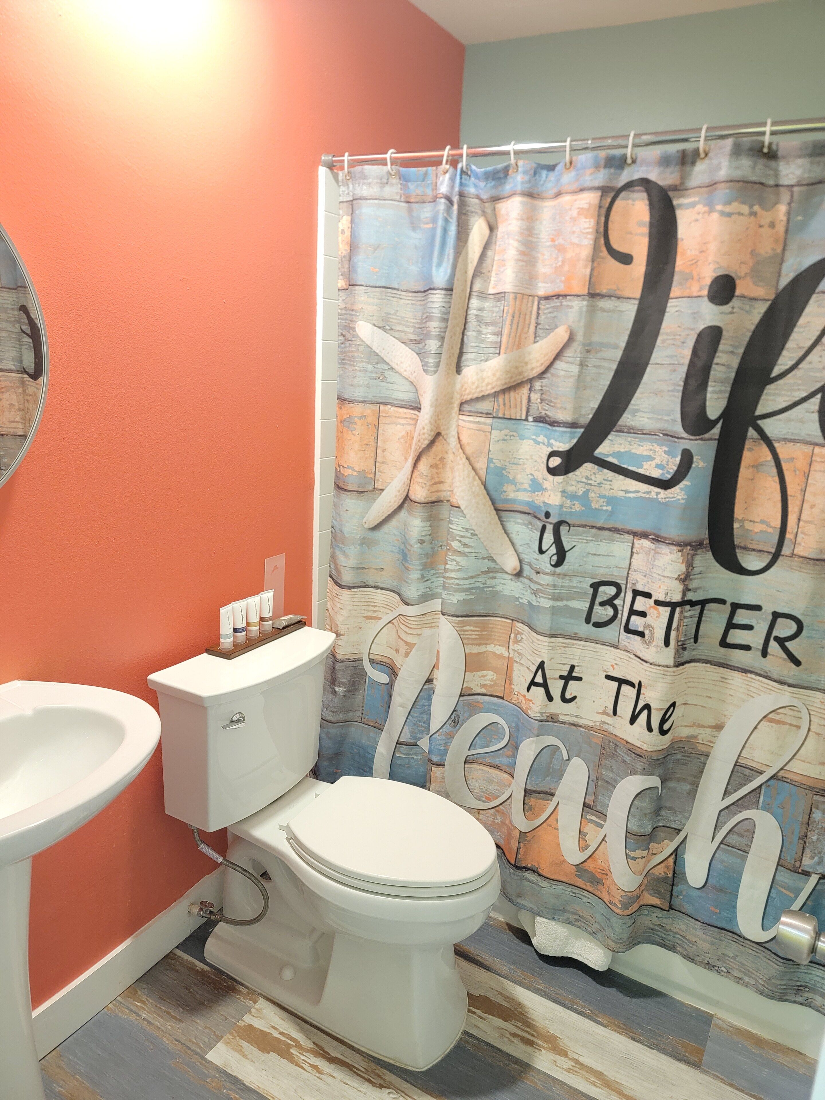 A bathroom with a toilet, sink, and shower curtain featuring a beach theme.