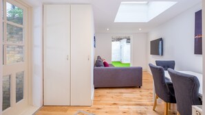 A modern room with a skylight, a grey sofa, a dining table with chairs, and a white wardrobe. - Marylebone Apartments (London)