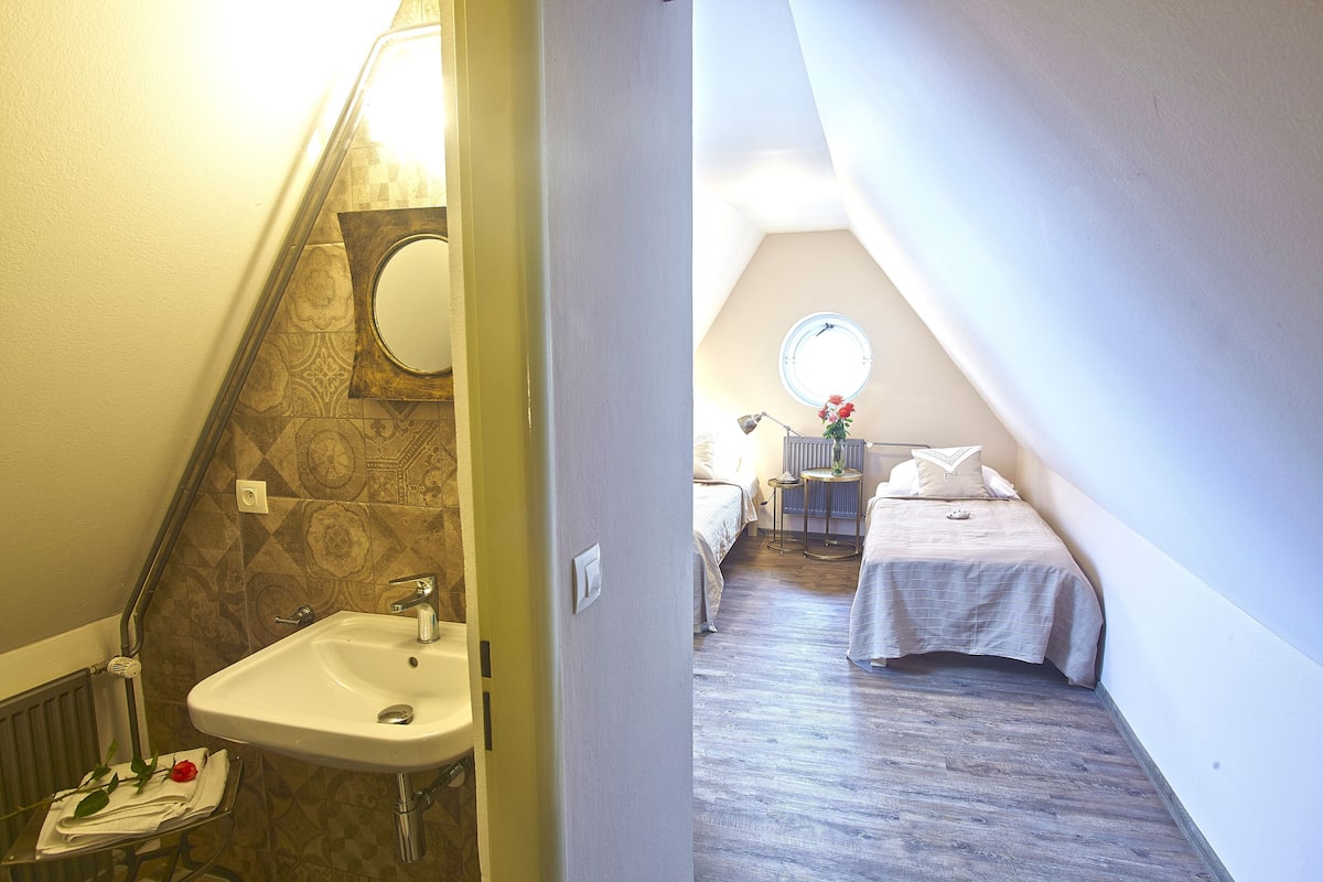 Quarto com uma cama, mesa de cabeceira, abajur e janela.