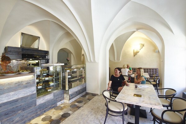 Un restaurante con decoración rústica, que incluye un mostrador con productos horneados y una zona de estar con mesas y sillas.