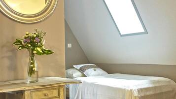 Une chambre à coucher avec un lit, une commode, un miroir et une lucarne.