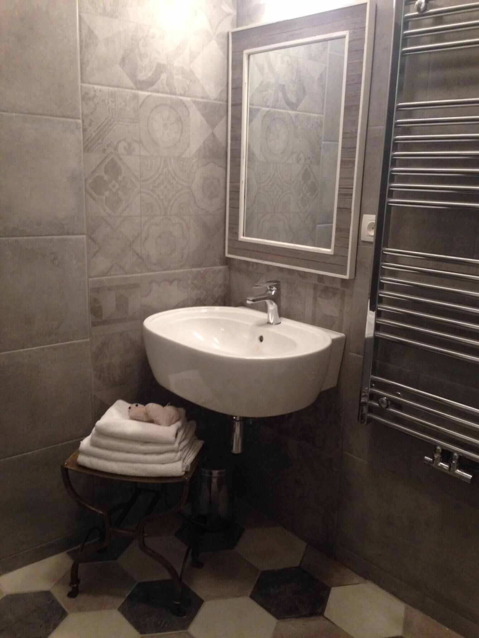 A bathroom with a white sink, a mirror, and a towel rack.