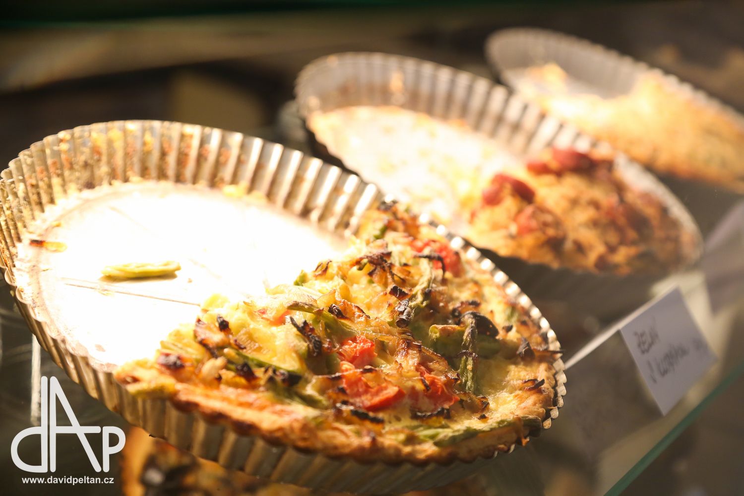 A display of quiches in a glass case with a price tag.