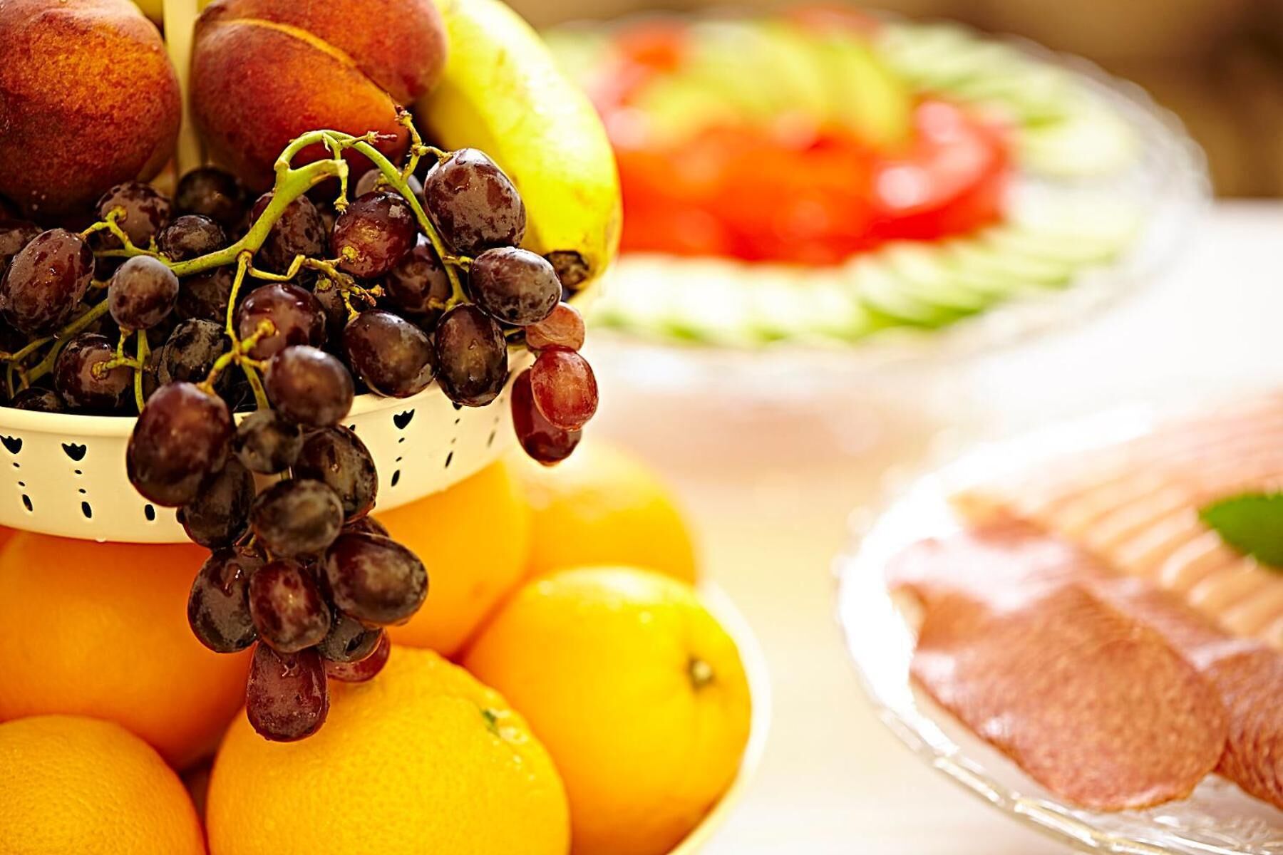 Un piatto di frutta con uva, arance e una fetta di melone.