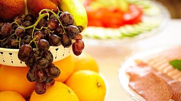 Un piatto di frutta con uva, arance e una fetta di melone.