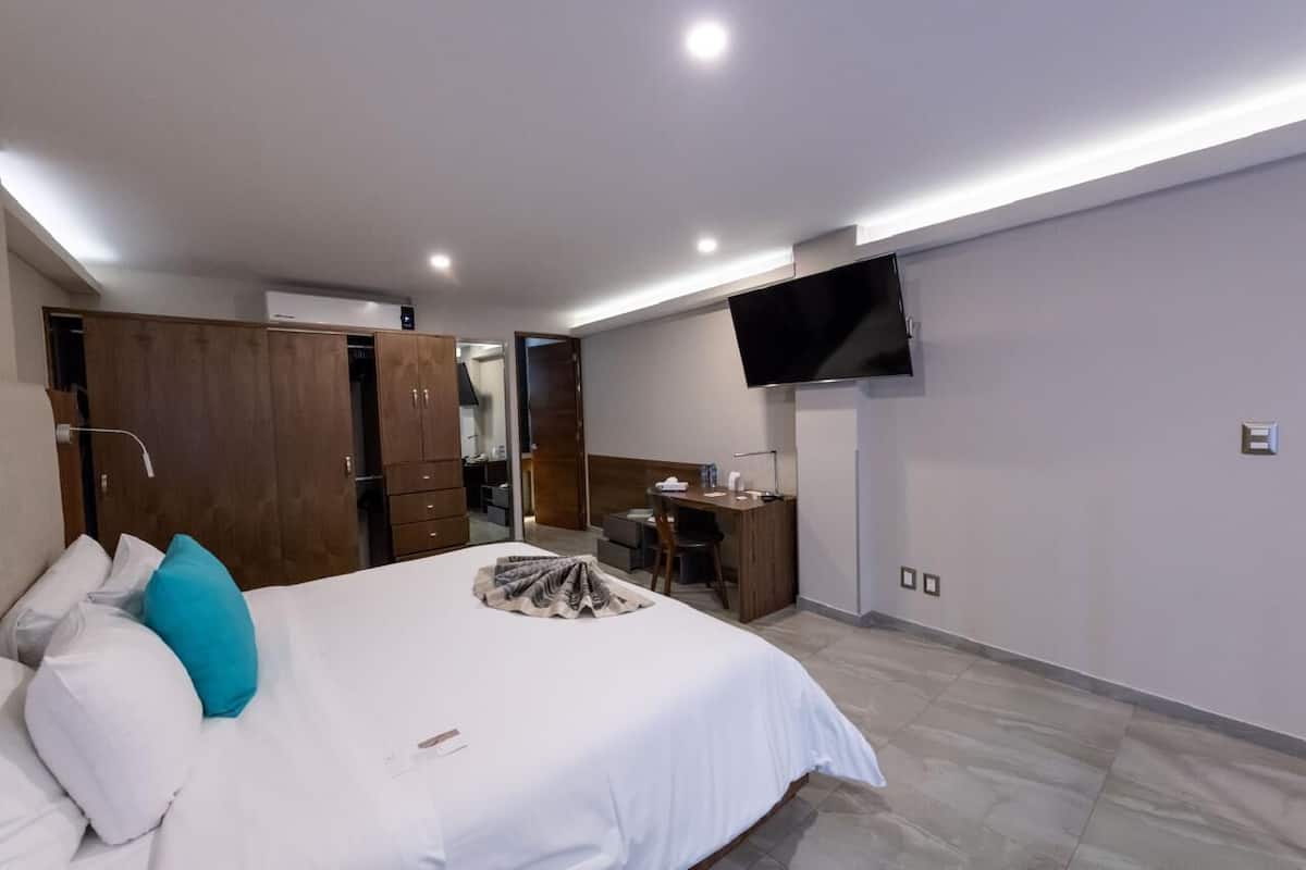 A hotel room with a bed, a desk, a TV, and a wardrobe.