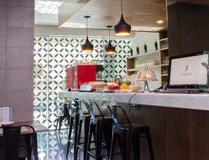 A modern bar area with a counter, bar stools, a coffee machine, and a computer monitor displaying 'J.TOWERS'.