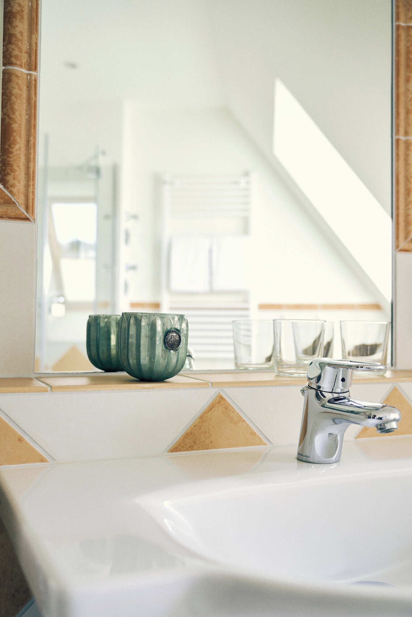 A bathroom with a sink, mirror, and a green ceramic bowl on the counter.