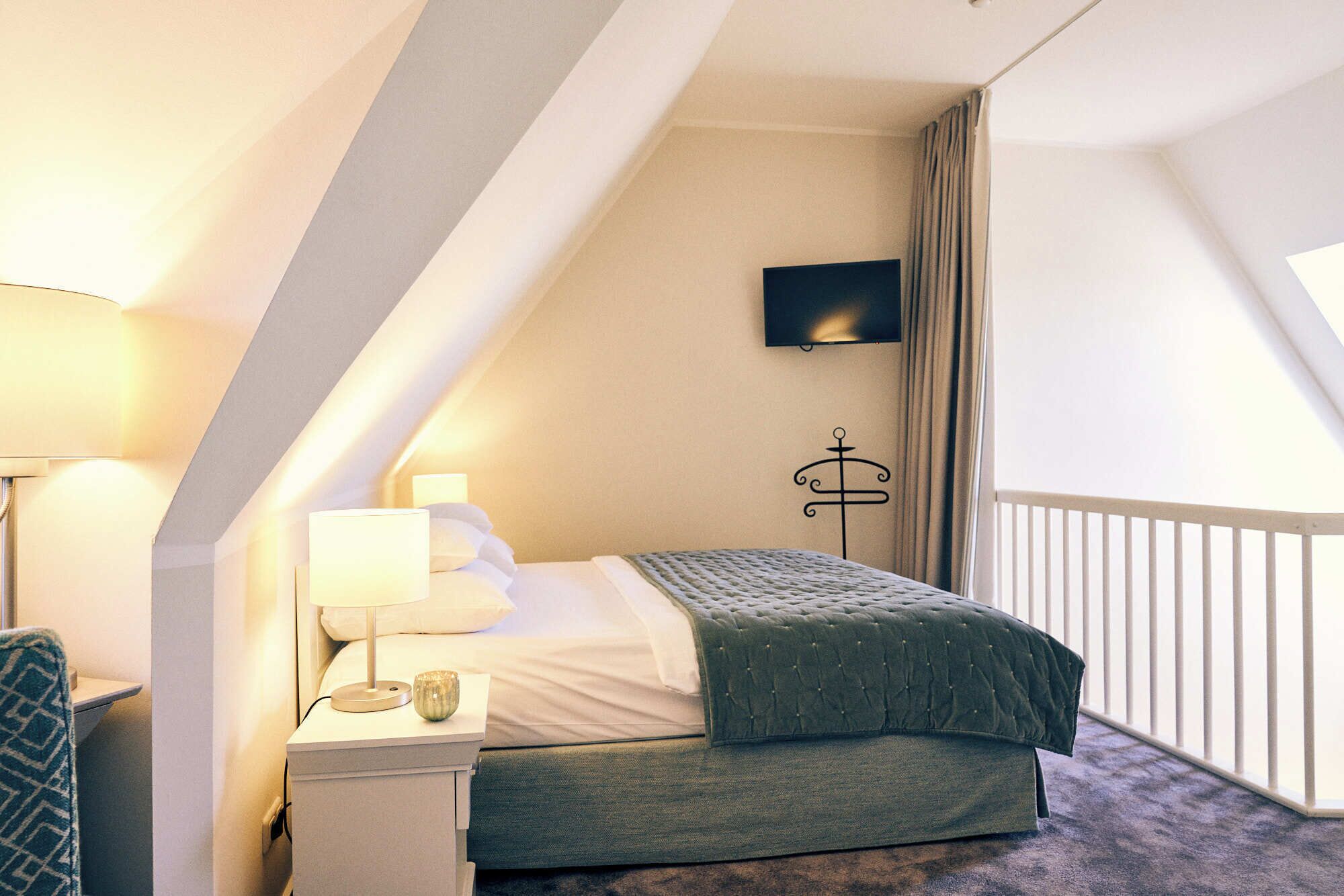 Une chambre à coucher avec un lit, des lampes de chevet, un téléviseur à écran plat et une fenêtre avec des rideaux.