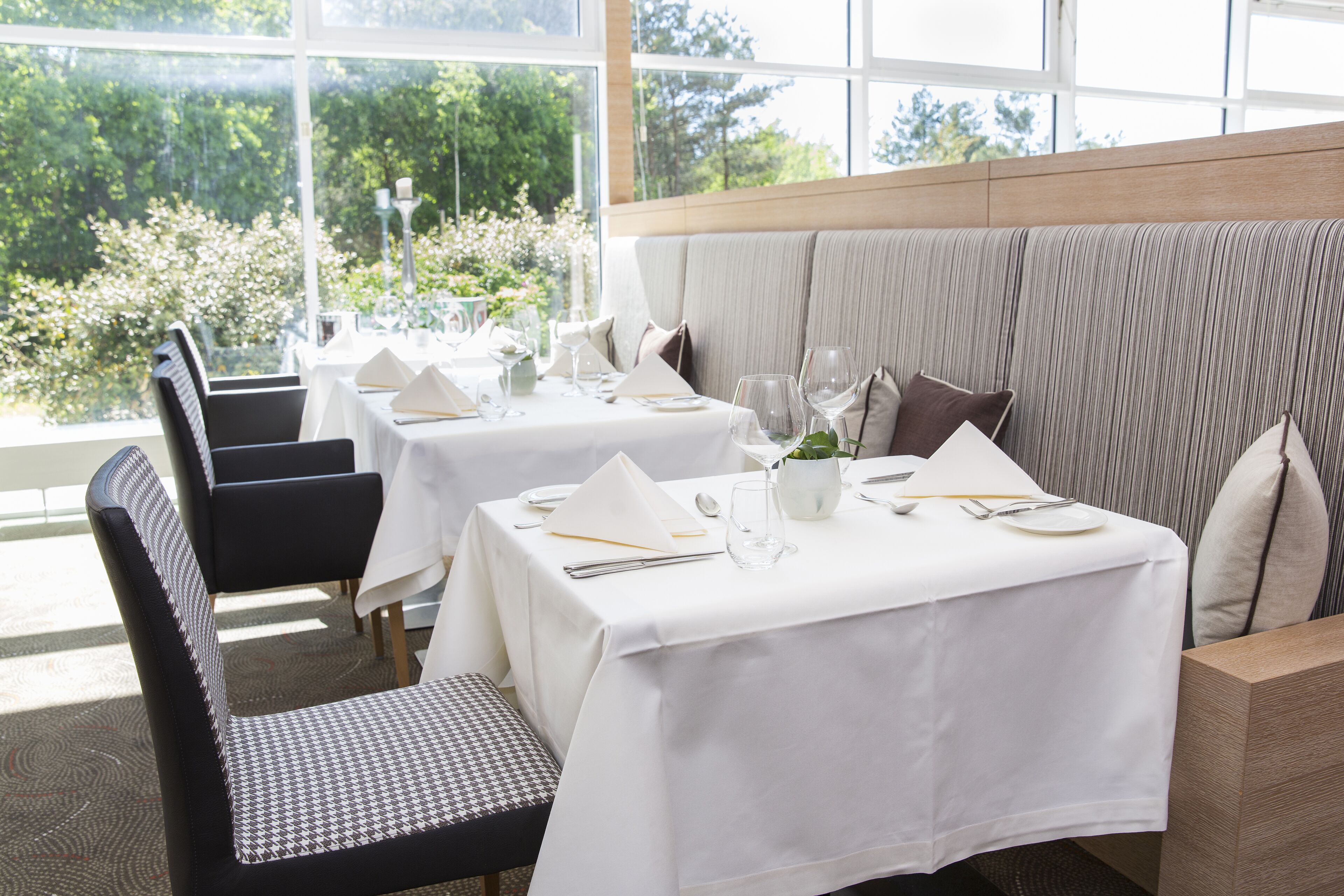 Un espace repas avec des tables dressées pour le service, agrémenté de nappes blanches et de couverts disposés avec soin.