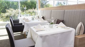 Un espace repas avec des tables dressées pour le service, agrémenté de nappes blanches et de couverts disposés avec soin.
