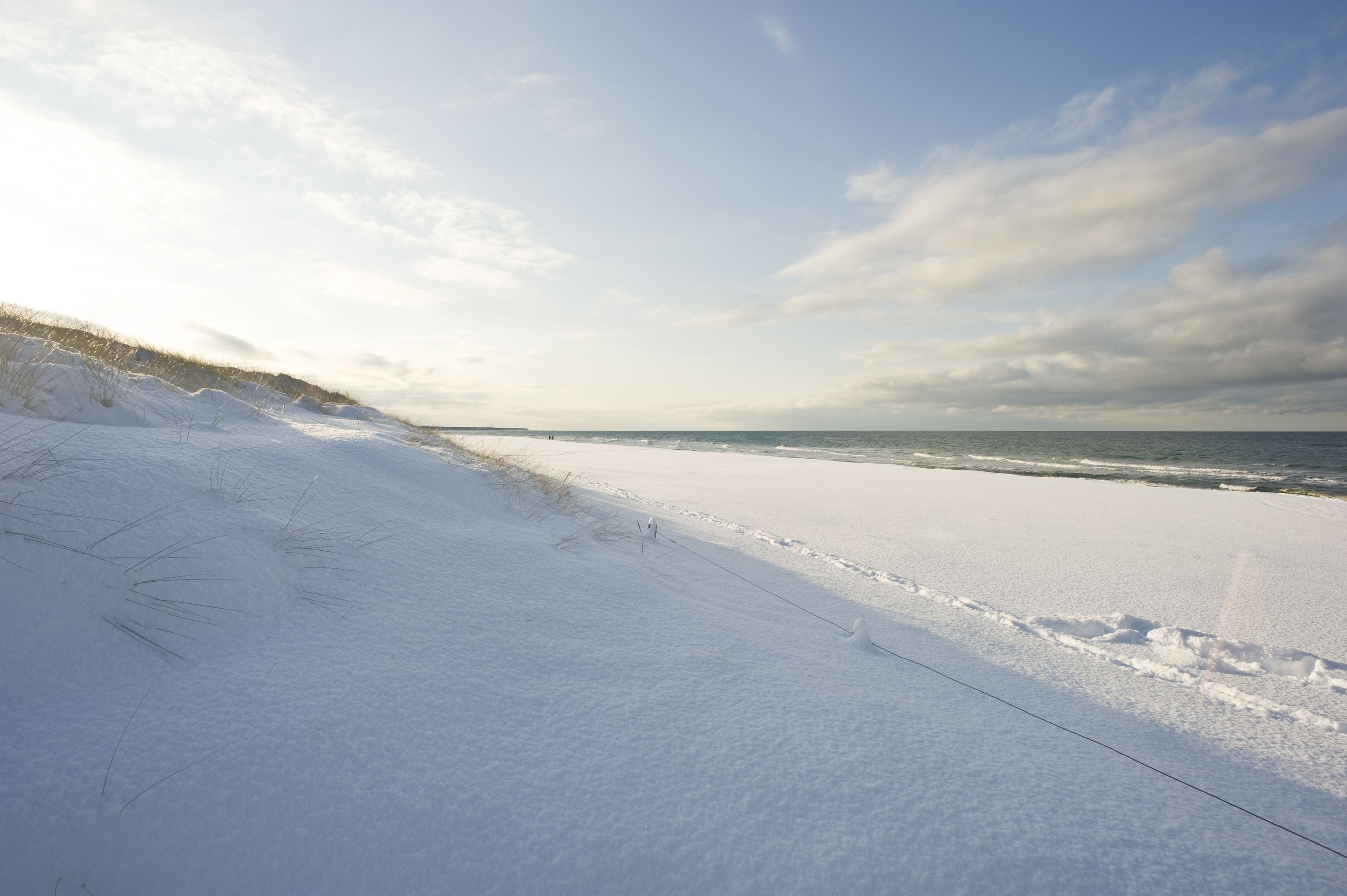 Ein schneebedeckter Strand unter blauem Himmel.