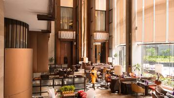 A spacious hotel lobby with a central bar area, seating arrangements, and a view of the outdoors.
