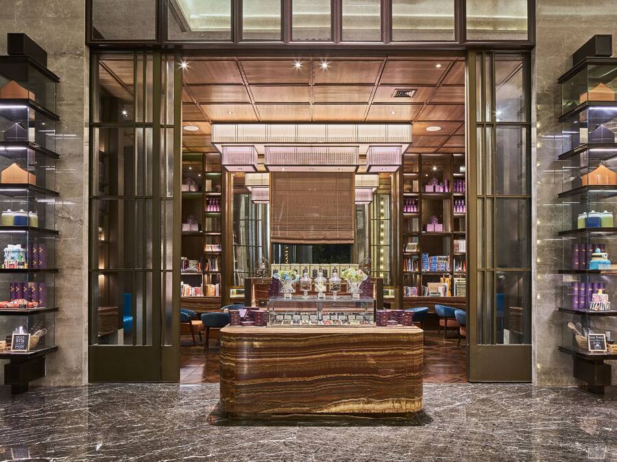 A modern interior with a central display table, glass shelving units, and a marble floor.