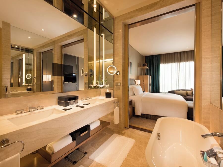 A modern hotel bathroom with a large sink, a bathtub, and a separate shower area.