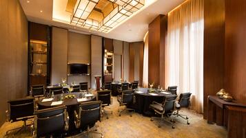 A conference room with multiple tables and chairs, a television, and a large window with curtains.