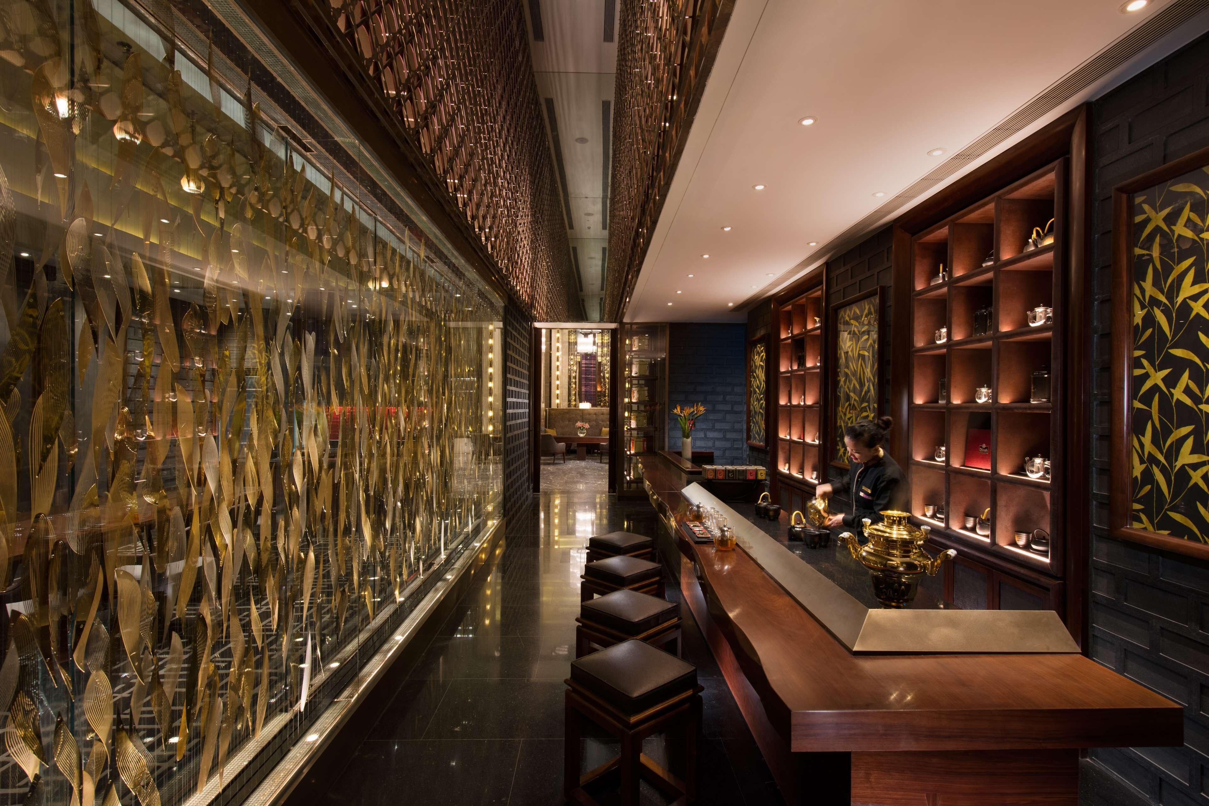 A bar area with stools, a counter, and shelves with decorative items.