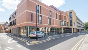 Un hôtel moderne avec une façade en briques, de grandes fenêtres et une voiture garée devant.