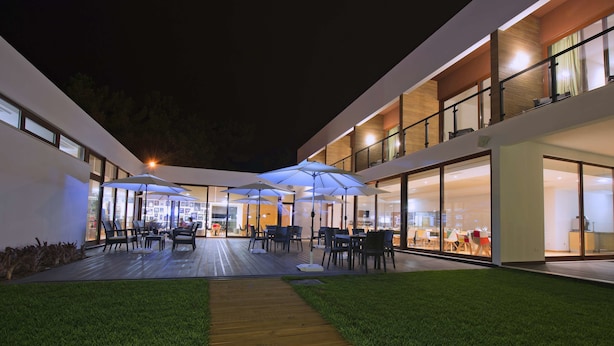 An outdoor patio area with multiple tables and chairs, umbrellas, and a wooden deck. - Villas da Fonte Leisure and Nature (Leiria)