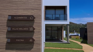 A modern building with signs for 'Alojamientos,' 'Villas Wellness,' and 'Piscina.' - Villas da Fonte Leisure and Nature (Leiria)