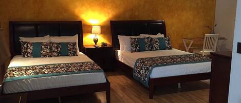 Habitación de hotel con dos camas, cada una con cabecera, mesitas de noche y lámparas.