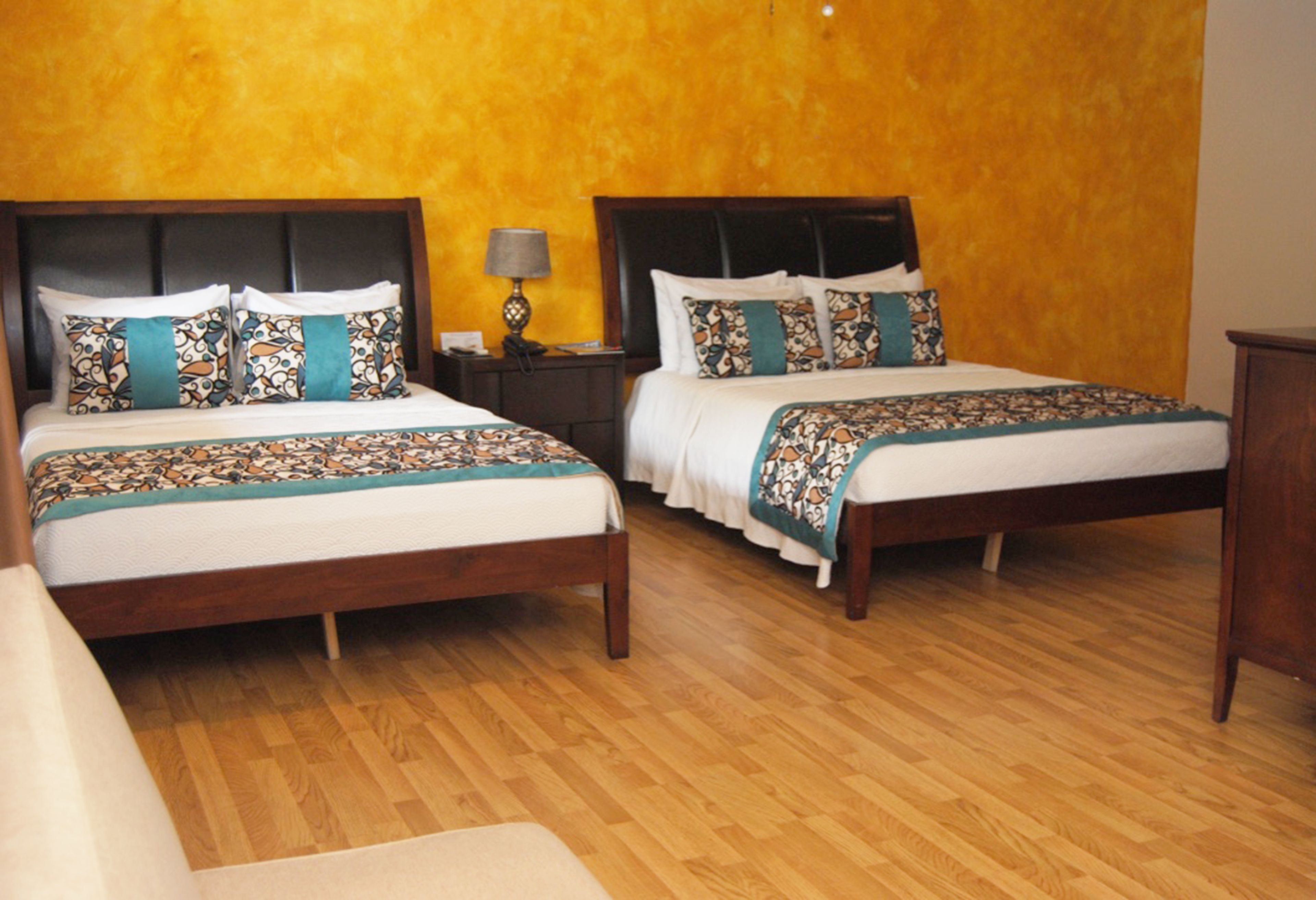 A hotel room with two double beds, wooden headboards, and a wooden floor.