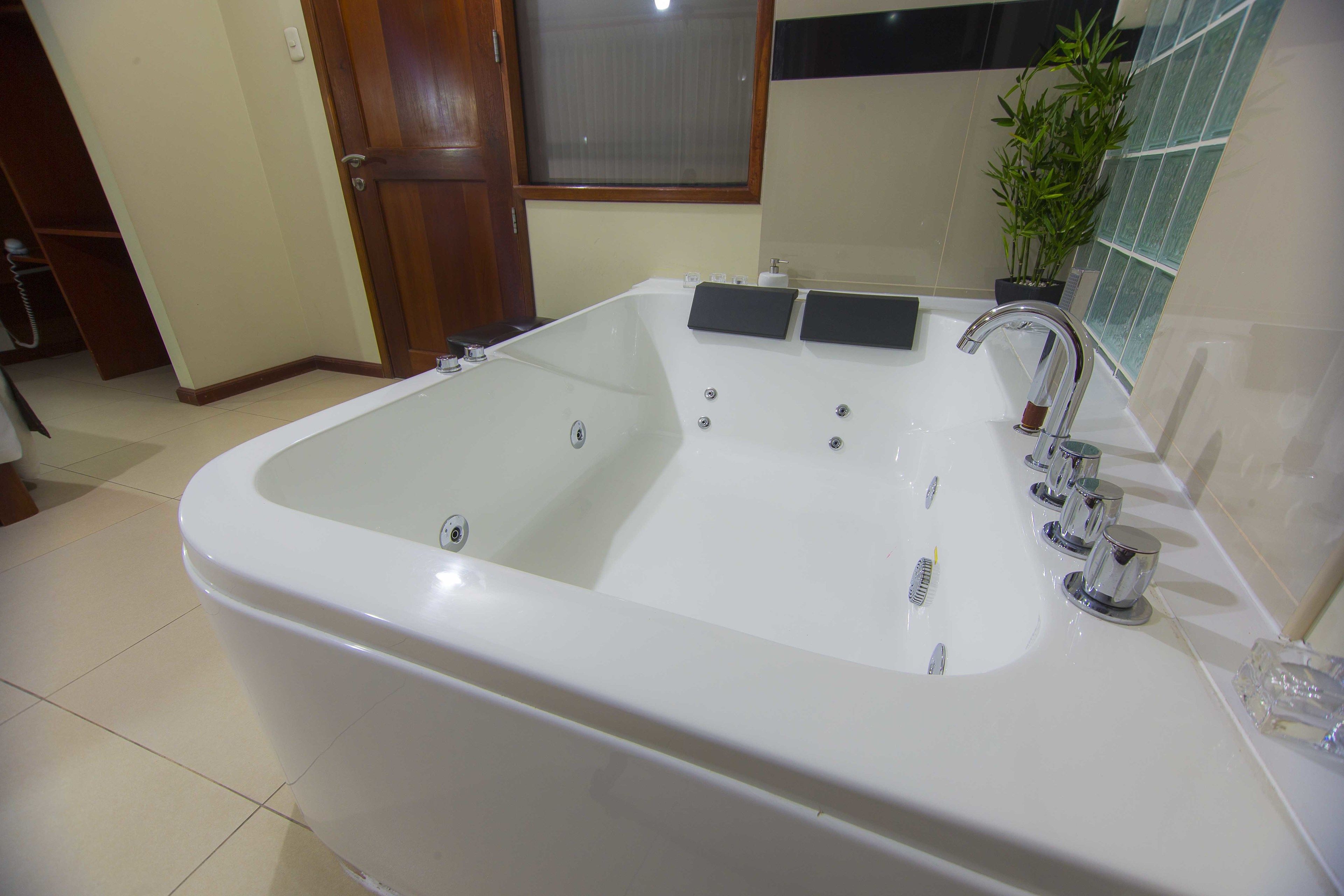 Eine große, weiße Badewanne mit modernem Wasserhahn und zwei Seifenschalen.
