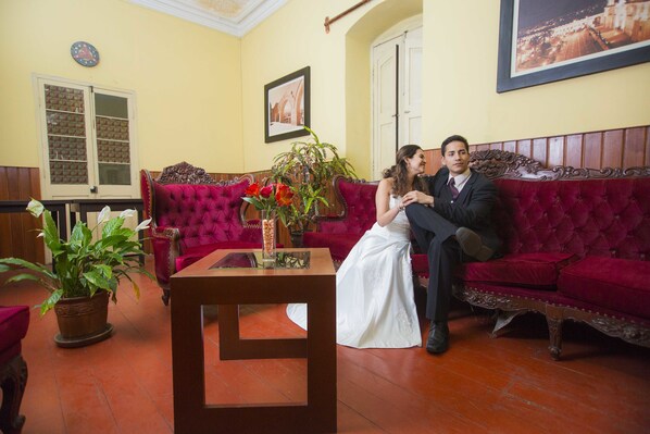 A room with a red upholstered sofa, a wooden coffee table, and a potted plant.