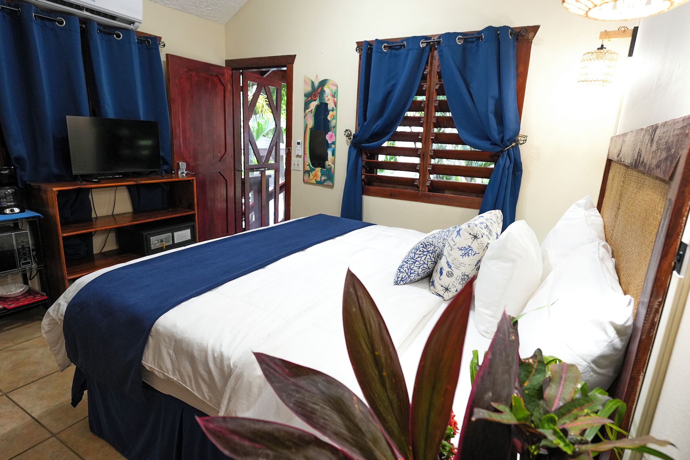 A hotel room with a bed, a television, a desk, and a window with curtains.