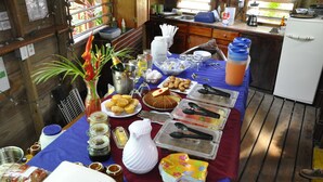 A table set with various food items and condiments, a white pitcher, and a decorative plant. - West Bay Lodge (Roatan)
