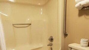 A bathroom with a bathtub, toilet, and a handrail. - Economy Inn (Rogersville)