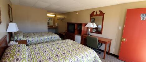 A hotel room with two beds, a desk, a chair, a television, and a mirror.