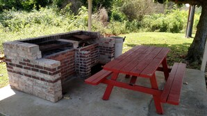 A brick barbecue grill with a picnic table. - Economy Inn (Rogersville)