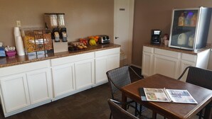 A small kitchenette with a coffee maker, toaster, and refrigerator. There is a dining table with chairs and a magazine on it. - Lake Eufaula Inn (Checotah)