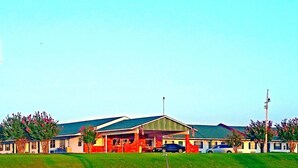 A motel with a large sign, multiple buildings, and parked cars. - Lake Eufaula Inn (Checotah)