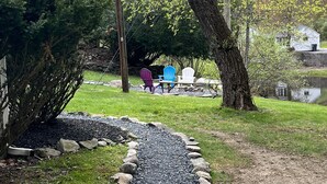 A gravel path bordered by rocks, leading to outdoor seating under trees. - Echo Valley Cottages (East Stroudsburg)