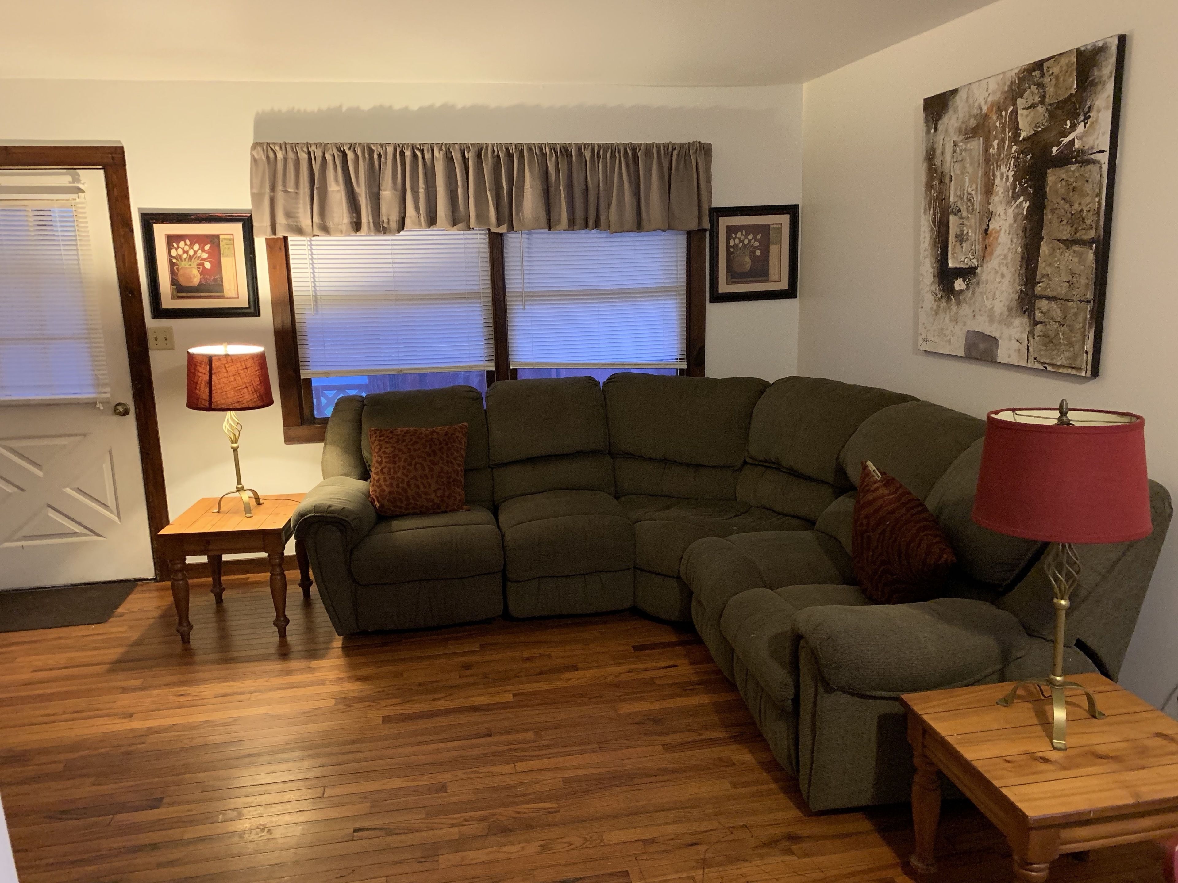 A living room with a sectional sofa, two lamps, a wooden coffee table, and a door.