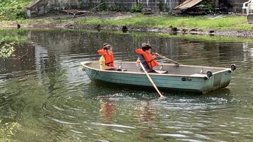 A small rowboat with two people paddling on a calm body of water.