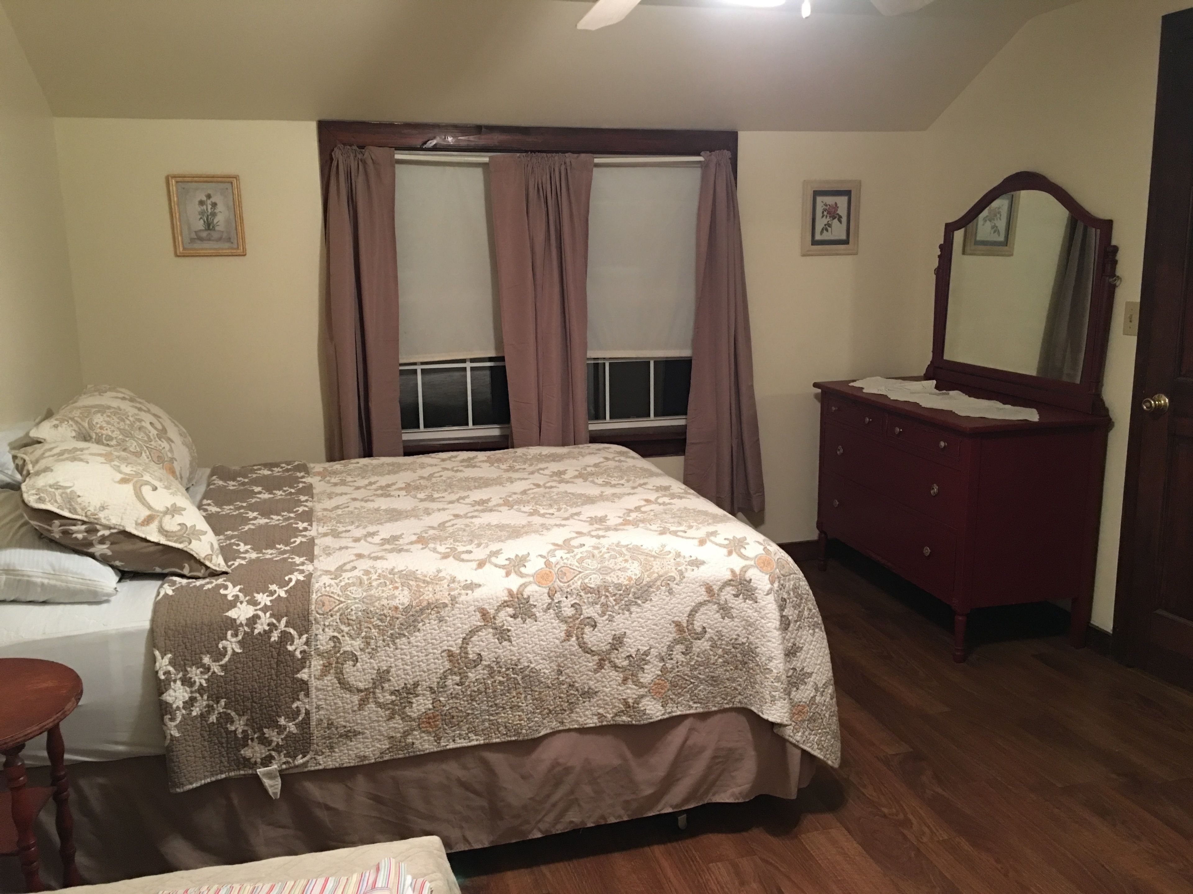 Un dormitorio con cama, cómoda y espejo.