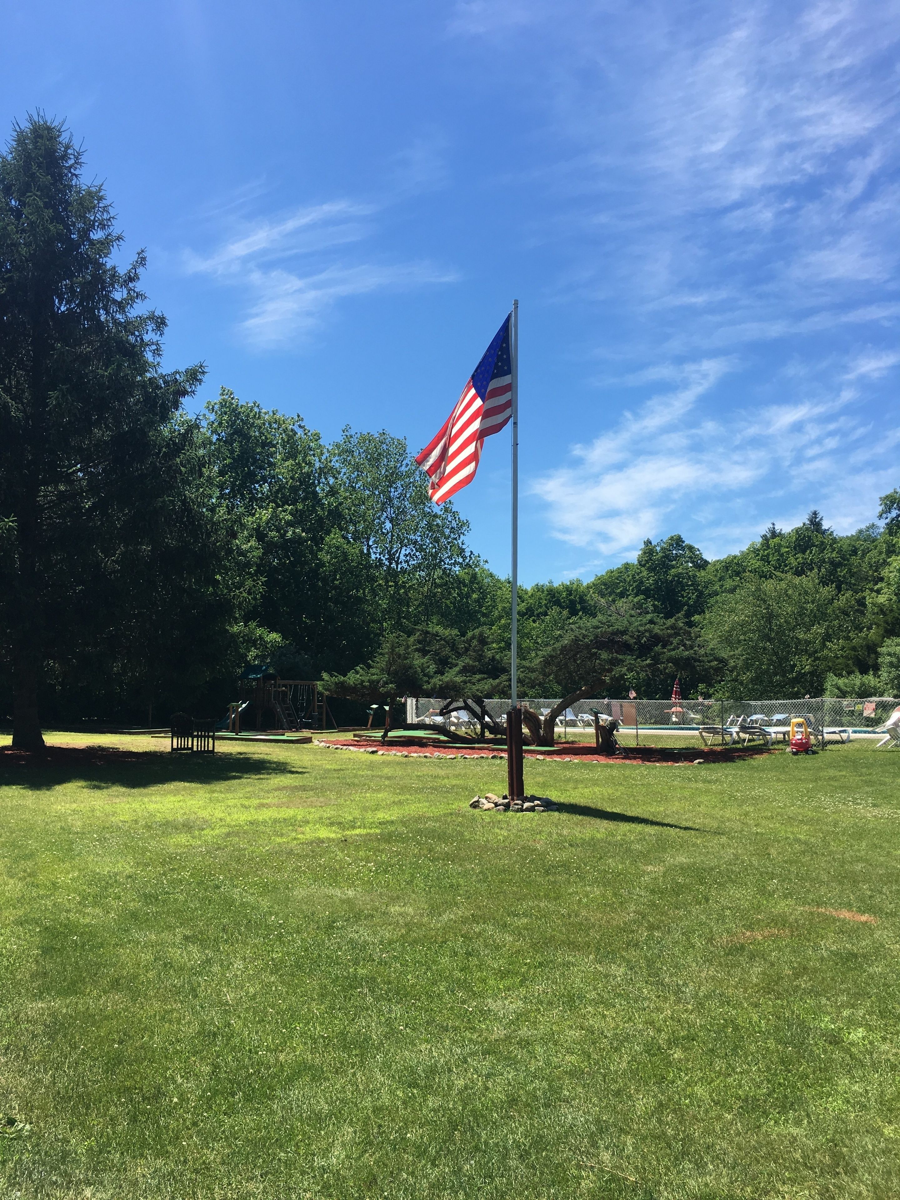 A grassy field with a flagpole and an American flag.