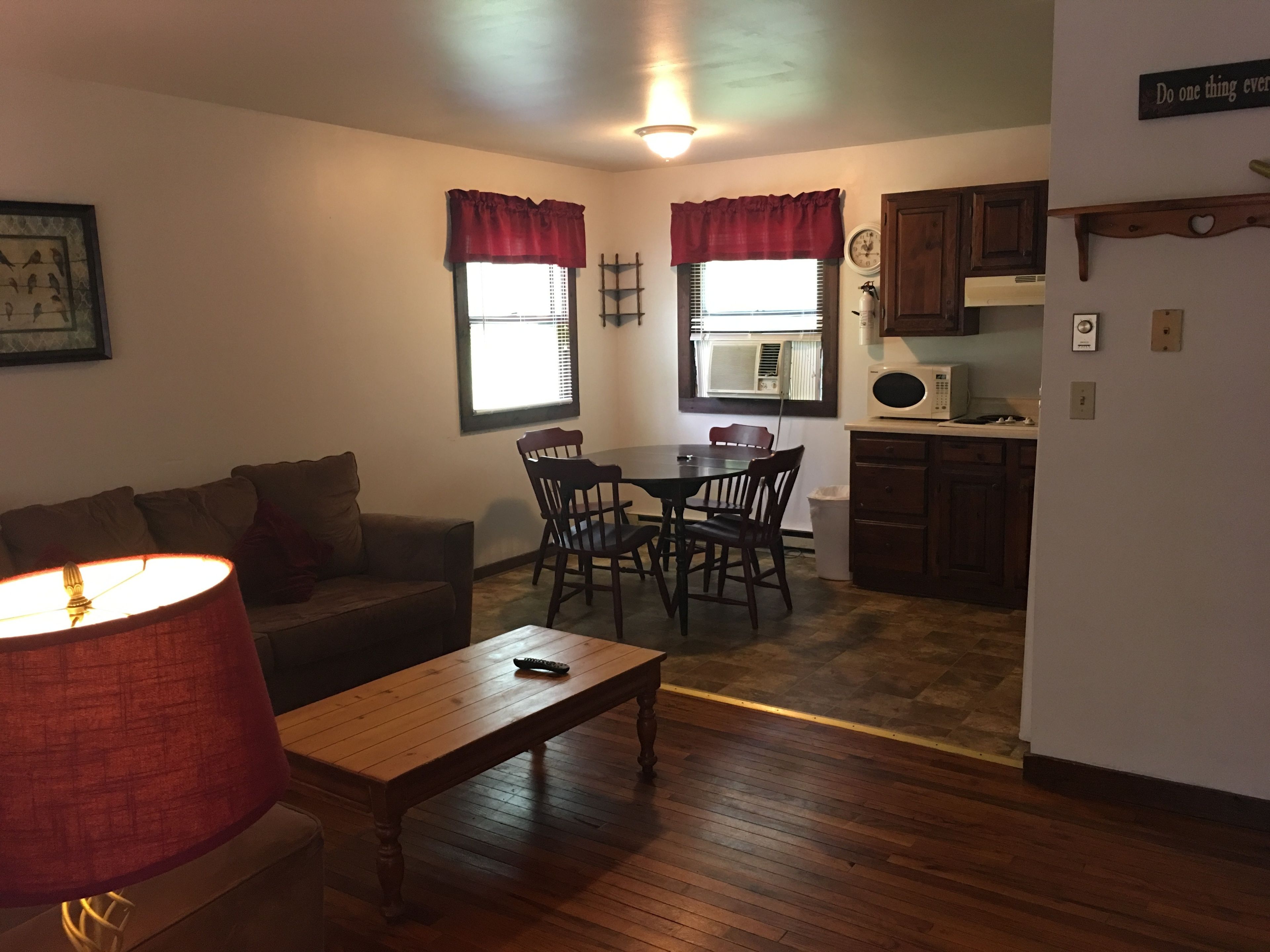 A compact living space with a dining area, kitchen, and a lamp.