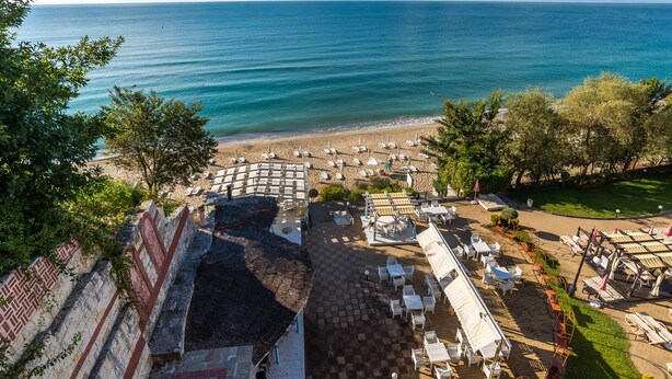 Un resort frente al mar con asientos exteriores, piscina y vista al océano.